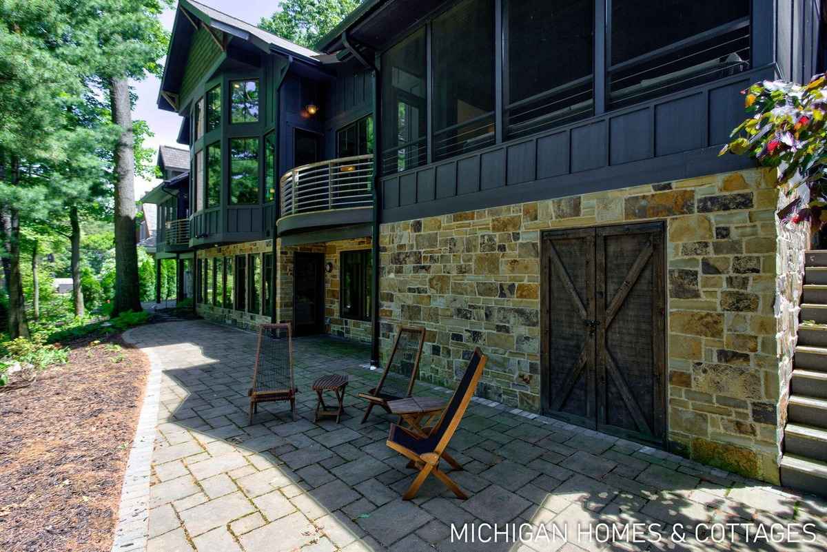 A large house with a stone exterior, a patio, and some outdoor seating is shown