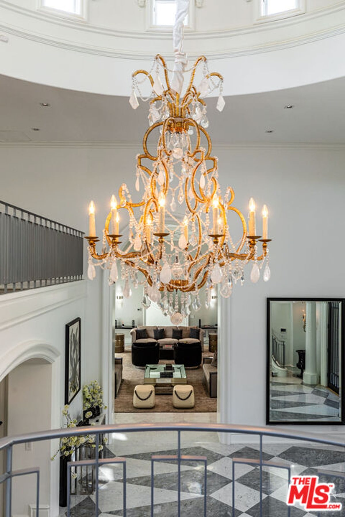 Ornate crystal chandelier hanging in a two-story foyer or entryway and chandelier is the central focus.