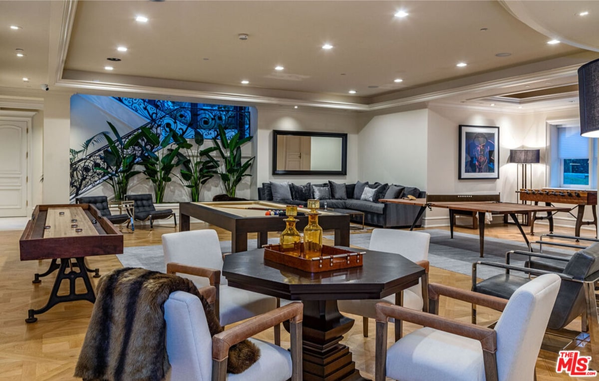 Game room or recreation area. There's a shuffleboard table, a pool table, and other furniture, including comfortable seating and a coffee table.