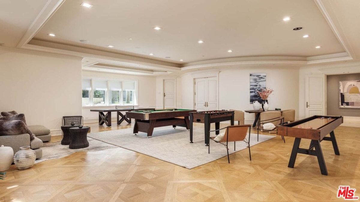 Bright game room with multiple game tables. There's a pool table, a shuffleboard table, and what appears to be a foosball table.