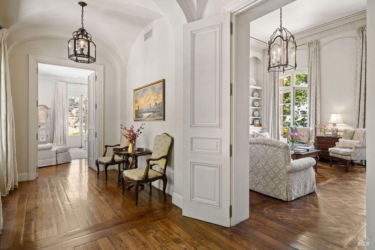 The hallway has high ceilings, light-colored walls, and hardwood floorings.