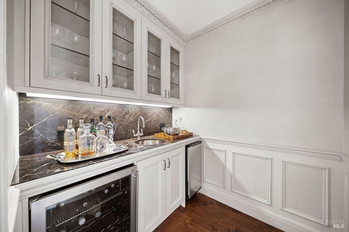 White cabinetry with glass-front upper cabinets displaying glassware