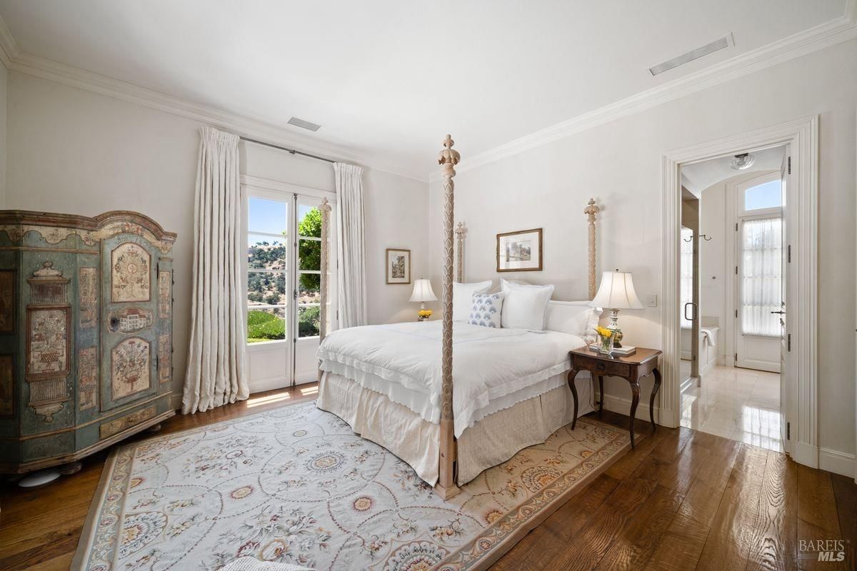 Bedroom with white walls, large bed with a tall ornate headboard