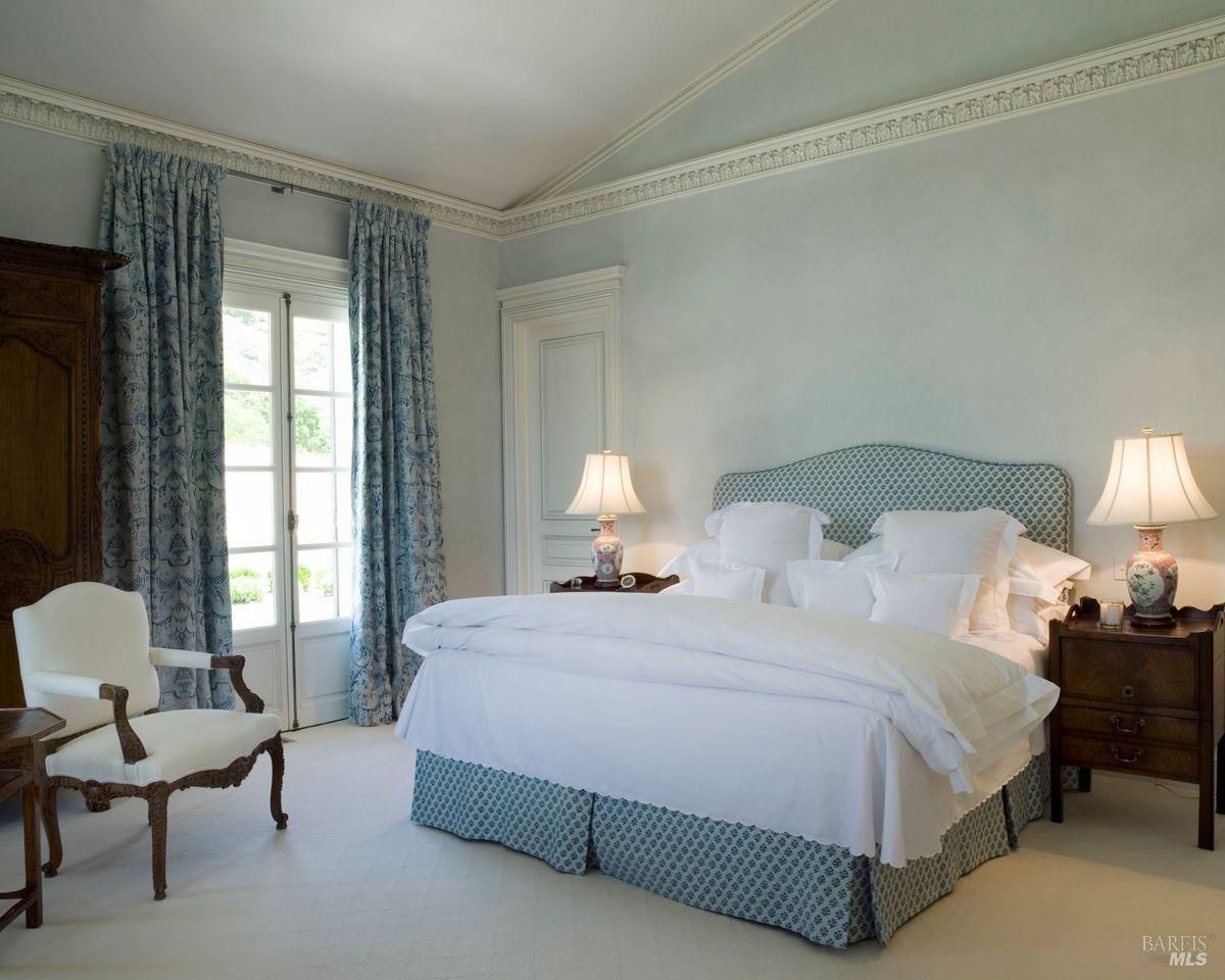 A large bed with white linens and light blue bedskirt