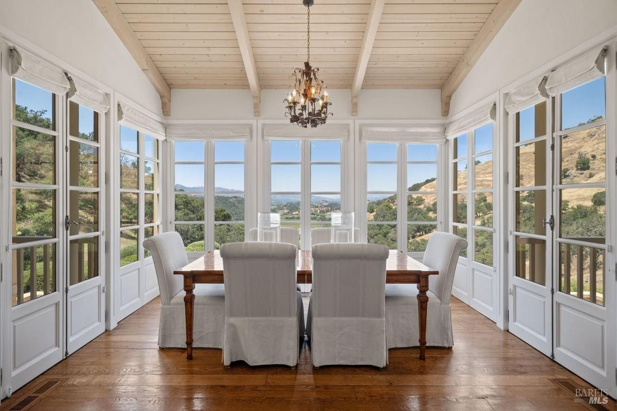 Dining room with a large, rectangular dining table with chairs with multiple large glass windows offering panoramic view