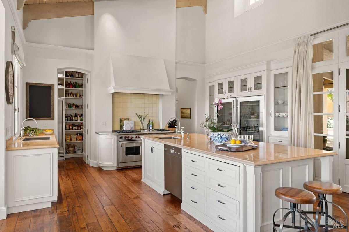 Kitchen with white cabinets, and a large island in the center