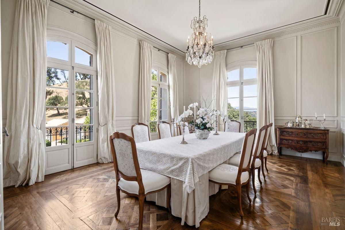 Dining room with chandelier and rectangular dining table covered with white tablecloth and surrounded with chairs