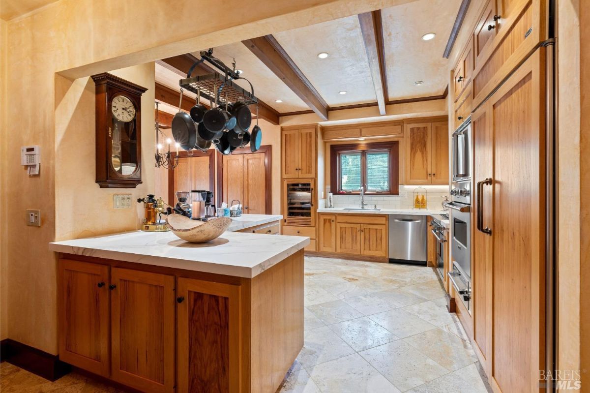 Open kitchen layout with a central island, hanging pot rack, and plenty of natural light.