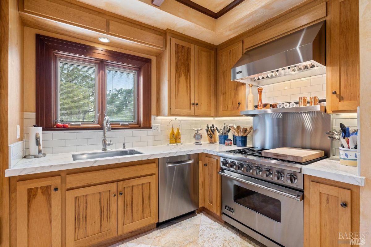 Functional kitchen corner featuring stainless steel appliances, wooden cabinets, and a window with outdoor views.