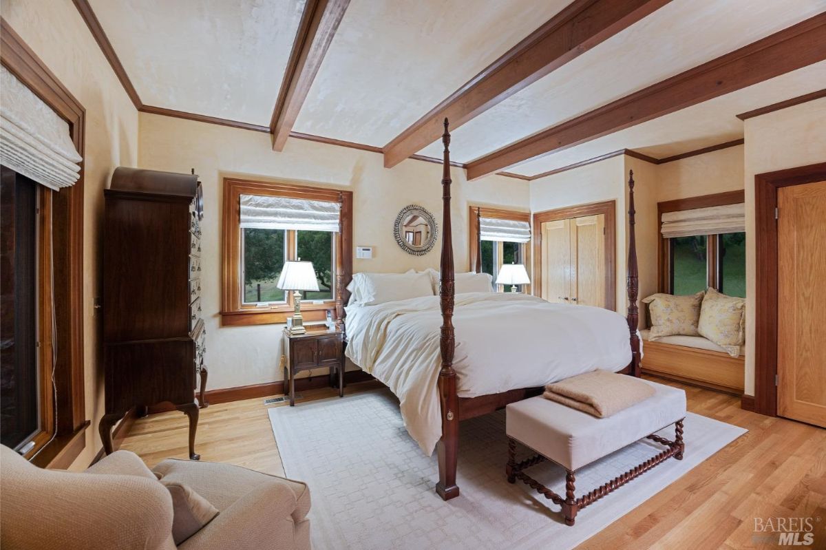 Elegant bedroom featuring a four-poster bed, wooden beams, and a cozy window seat.