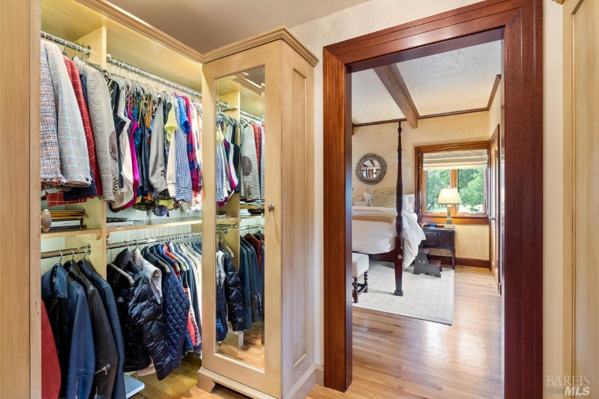 Spacious wardrobe with mirrored cabinets and neatly arranged clothing racks.