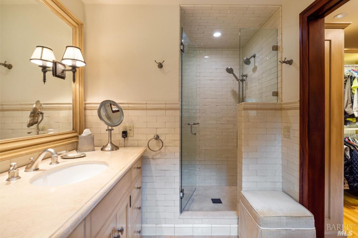 Bathroom showcases a sleek vanity with a large mirror and a glass-enclosed shower.