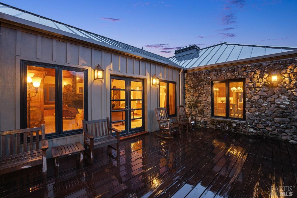 Outdoor deck features wooden seating and warm lighting against a stone wall backdrop.