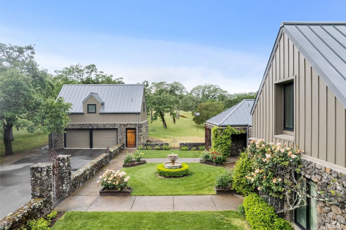 Front courtyard presents a well-manicured lawn with a fountain centerpiece and vibrant flower beds.