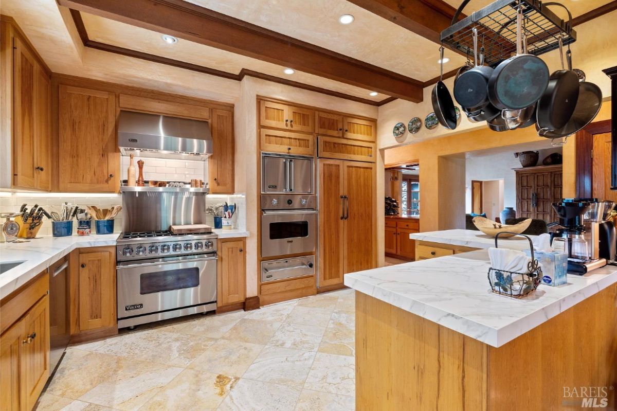 Spacious kitchen combining a functional cooking area, storage cabinets, and decorative ceiling beams.