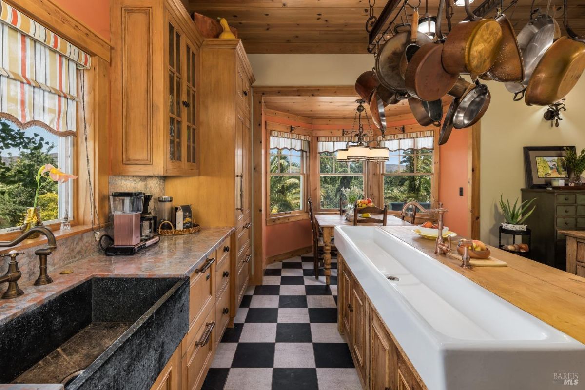 Kitchen exudes a rustic warmth with its wood-paneled ceiling, custom cabinetry, and unique farmhouse-style sink.