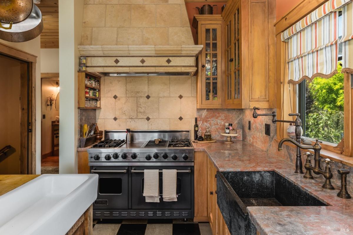 The custom wood cabinetry, stone backsplash, and farmhouse sink create a warm and inviting atmosphere, while the high-end range and ample counter space cater to the needs of any home chef.