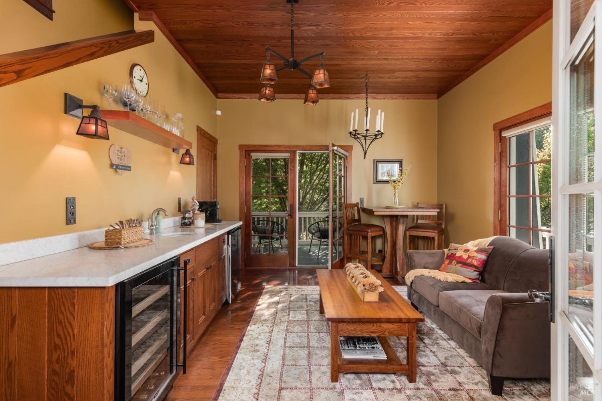 Room contains bar with stools, sofa, coffee table, and doors leading to a balcony.