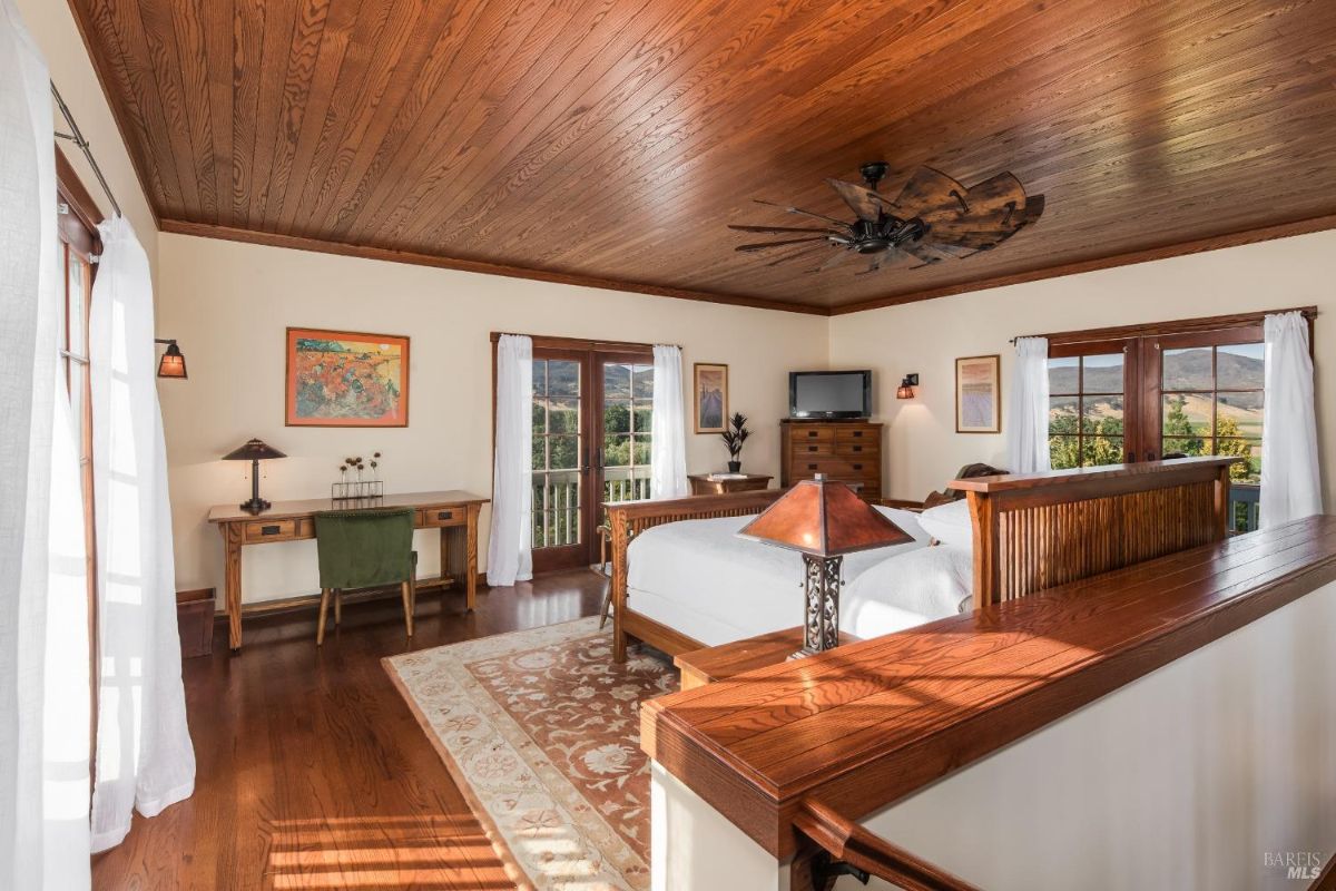 Bedroom includes bed, desk, television, and doors leading to a balcony.