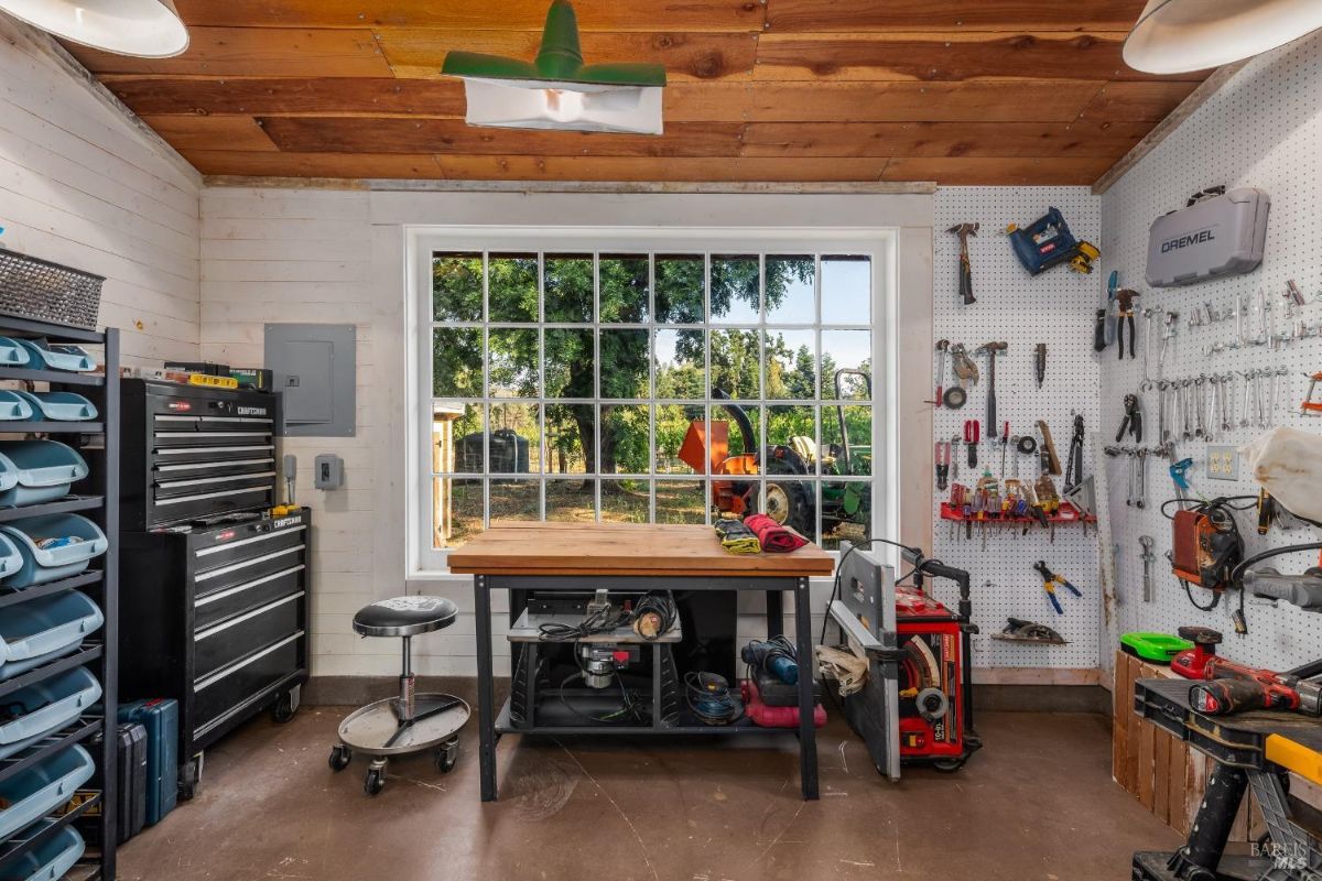 Workshop has pegboard tool organization, workbench, toolbox, and window.