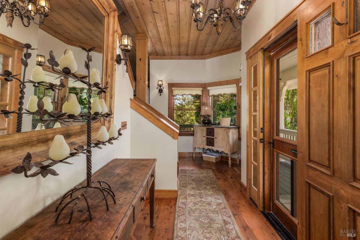 Wooden entryway with a staircase, natural light, and rustic decor including a pear-shaped ornament tree.