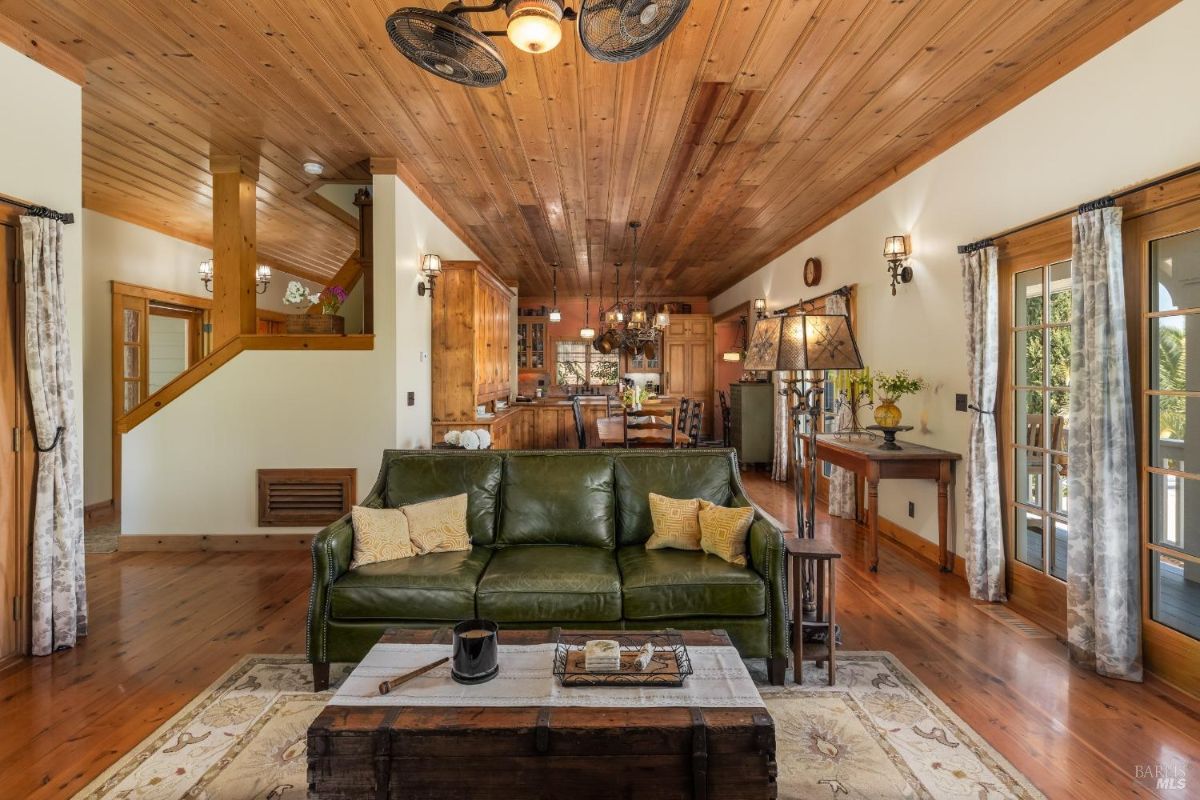 Open living and dining area with exposed wooden ceiling and an adjacent kitchen.