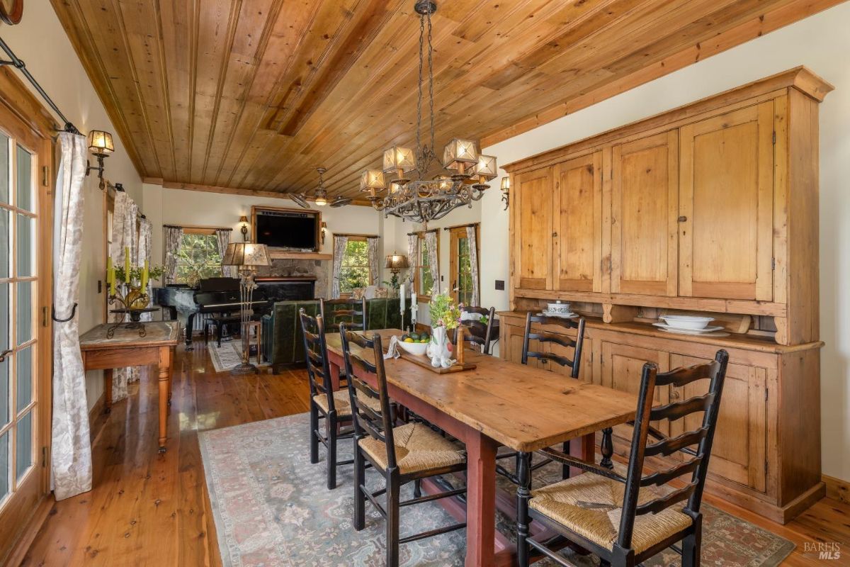 Dining area featuring a rustic wooden table, chandelier, and views into the living room.