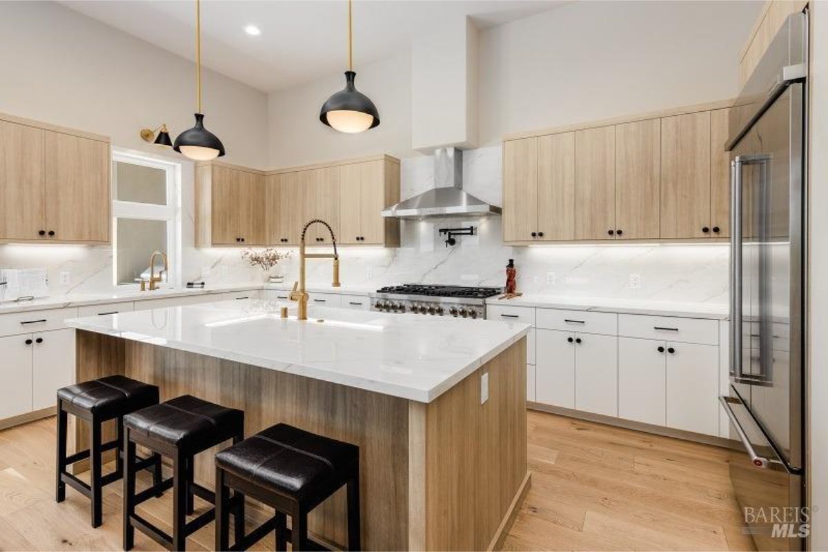 Kitchen close-up with marble countertops, wooden cabinetry, and gold fixtures.