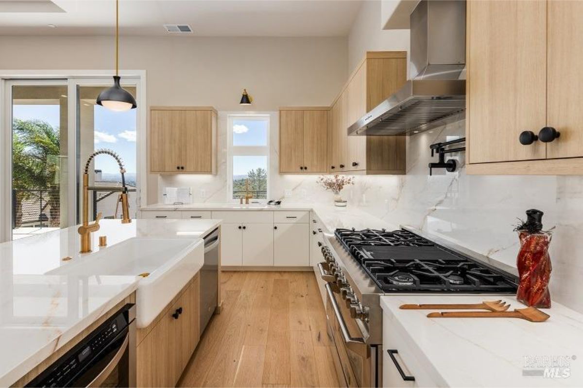 Sleek kitchen design includes a statement faucet, marble counters, and stainless-steel appliances.