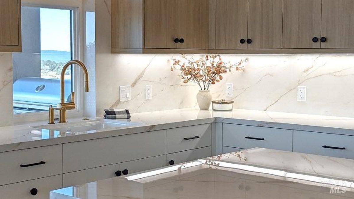 Kitchen corner highlights elegant countertops, a golden faucet, and a minimalist backsplash.