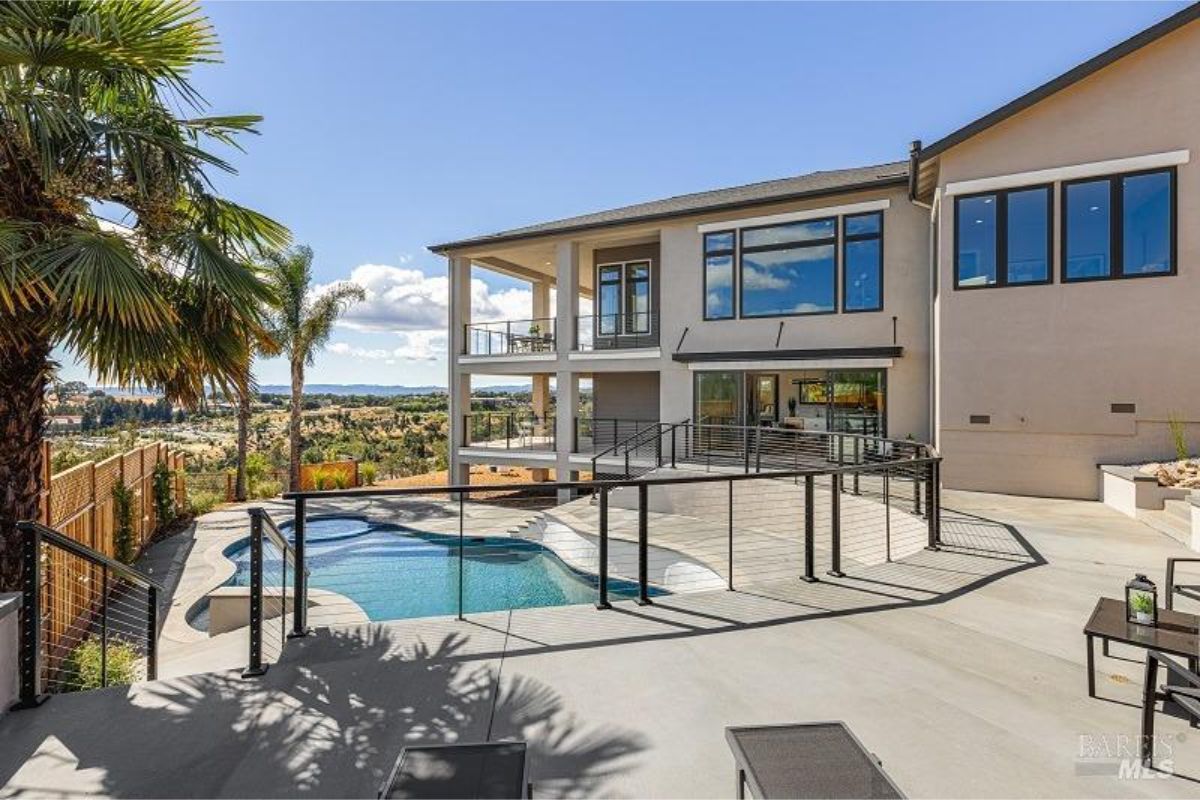 Modern home with a swimming pool and a patio overlooking a scenic landscape.