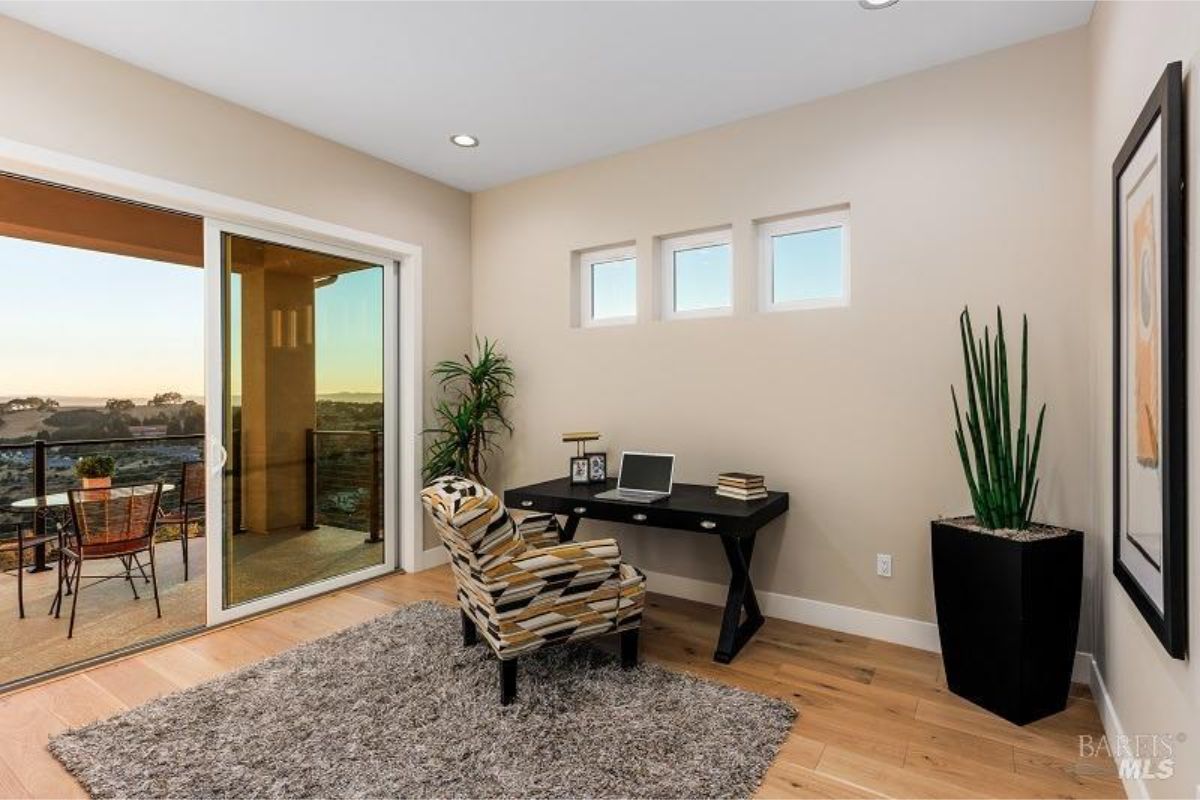 Home office setup with sliding doors opening to a private balcony and outdoor views.