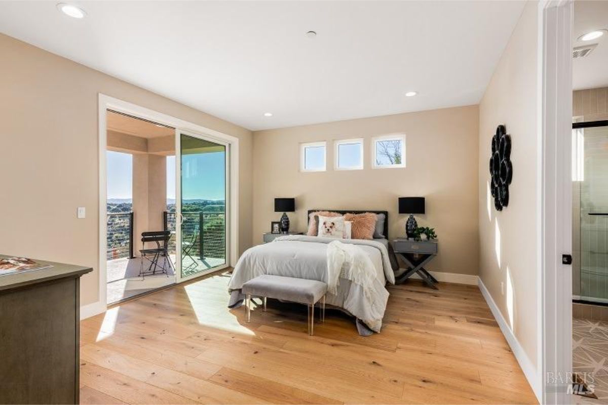 Bright bedroom with sliding doors leading to a private balcony overlooking the landscape.