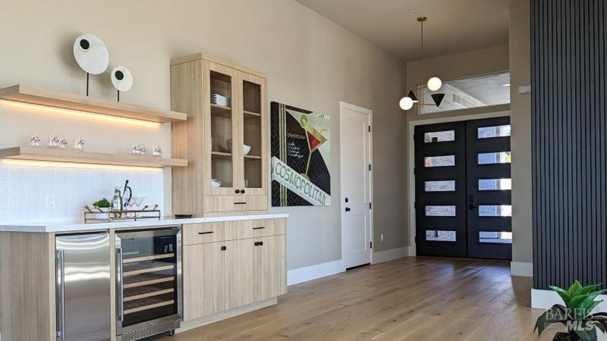 Entryway has wood floors, a bar area with a wine fridge, and a door.