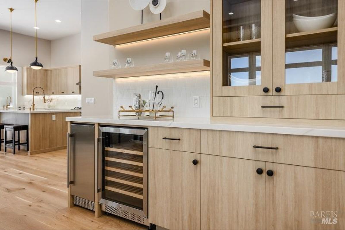 Wet bar area incorporates modern wooden cabinetry and a wine fridge for convenient entertaining.