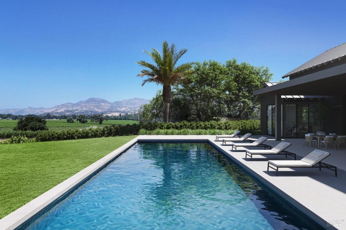 Highlights a rectangular pool bordered by a well-maintained lawn, lounge chairs, and scenic mountain views in the background.