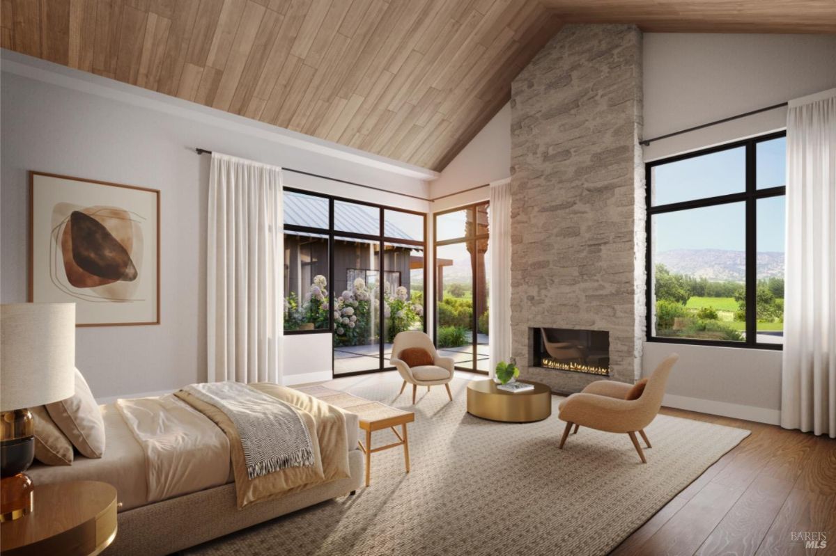 Bedroom with large windows, a stone fireplace, and a neutral color scheme overlooking greenery.