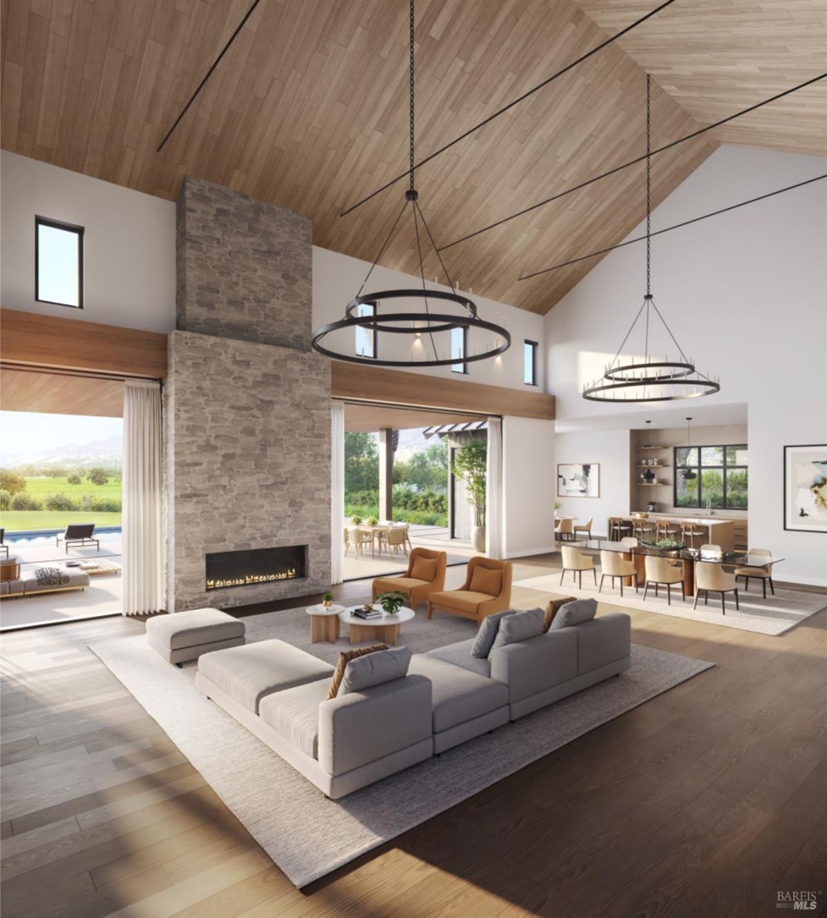 Interior space combining a living room, dining area, and kitchen under a vaulted wooden ceiling with large chandeliers.