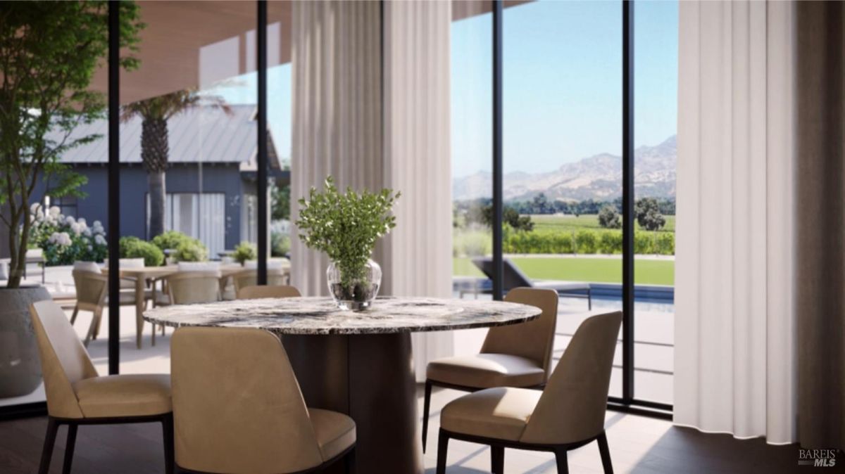 Dining space with a marble round table, beige chairs, and floor-to-ceiling glass offering outdoor views.