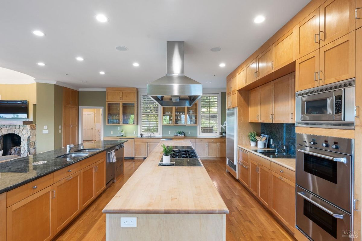 Modern cooking area featuring double ovens, a sleek range hood, and ample counter space.