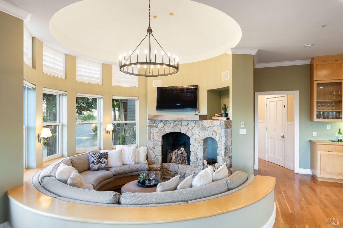 A rounded seating area with a stone fireplace and a central chandelier, offering a cozy and inviting atmosphere.