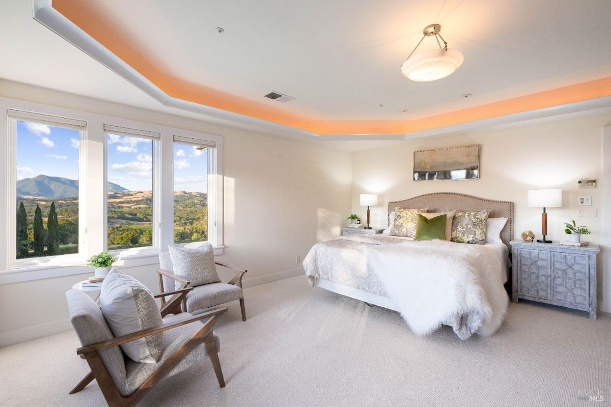 Elegant bedroom with soft lighting, plush bedding, and scenic mountain views through large windows.