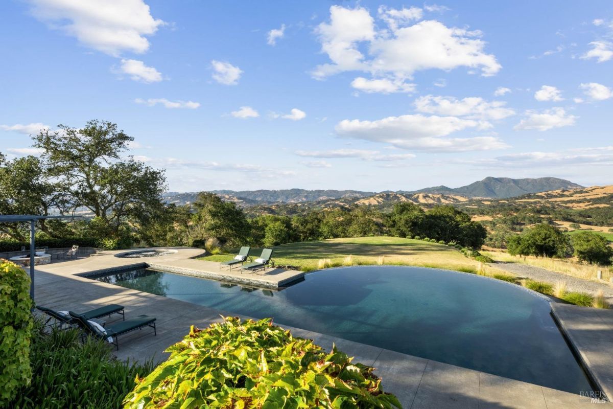 An infinity pool and spa surrounded by nature, offering sweeping views of rolling hills.