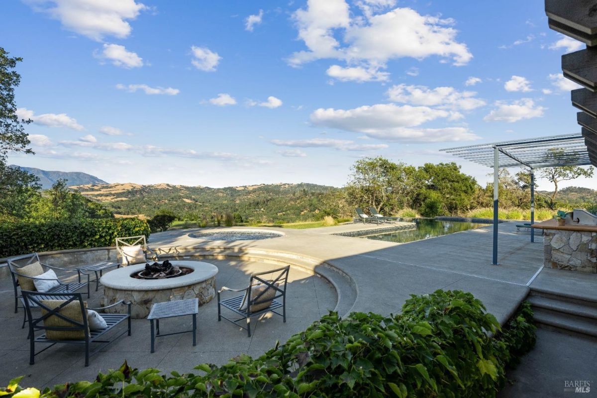 A serene outdoor space with a fire pit, seating area, and infinity pool overlooking the picturesque scenery.