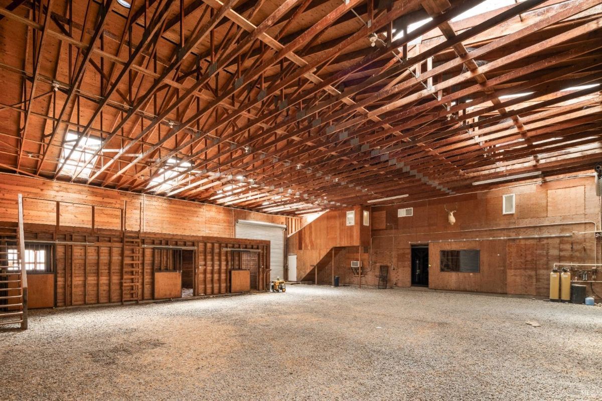 Barn with high exposed wooden ceilings, open floor space, and ample natural light streaming through skylights.