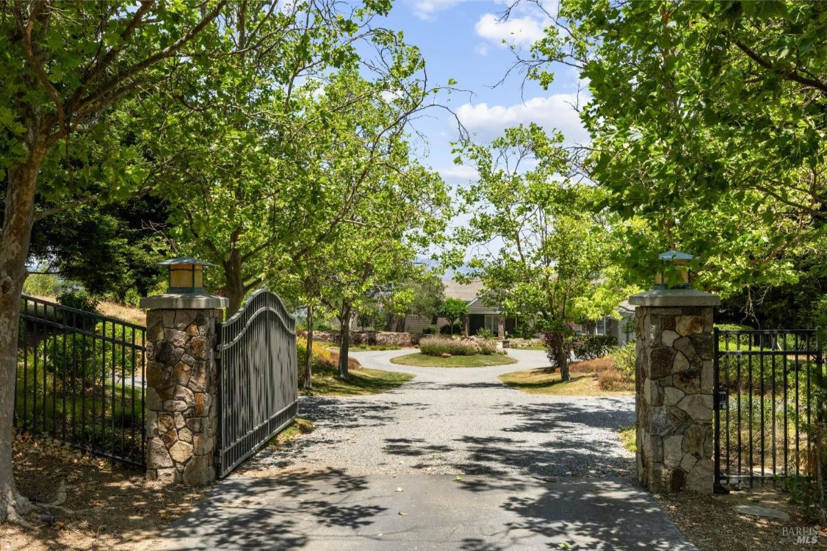 The gated entrance offers privacy and sets a welcoming tone with stone pillars and lush greenery.