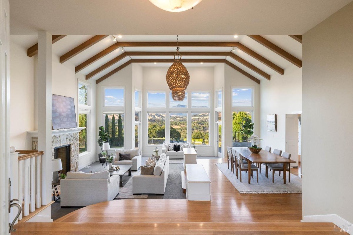 A wide-angle shot of the living and dining areas showcasing elegant decor, natural lighting, and vaulted ceilings.