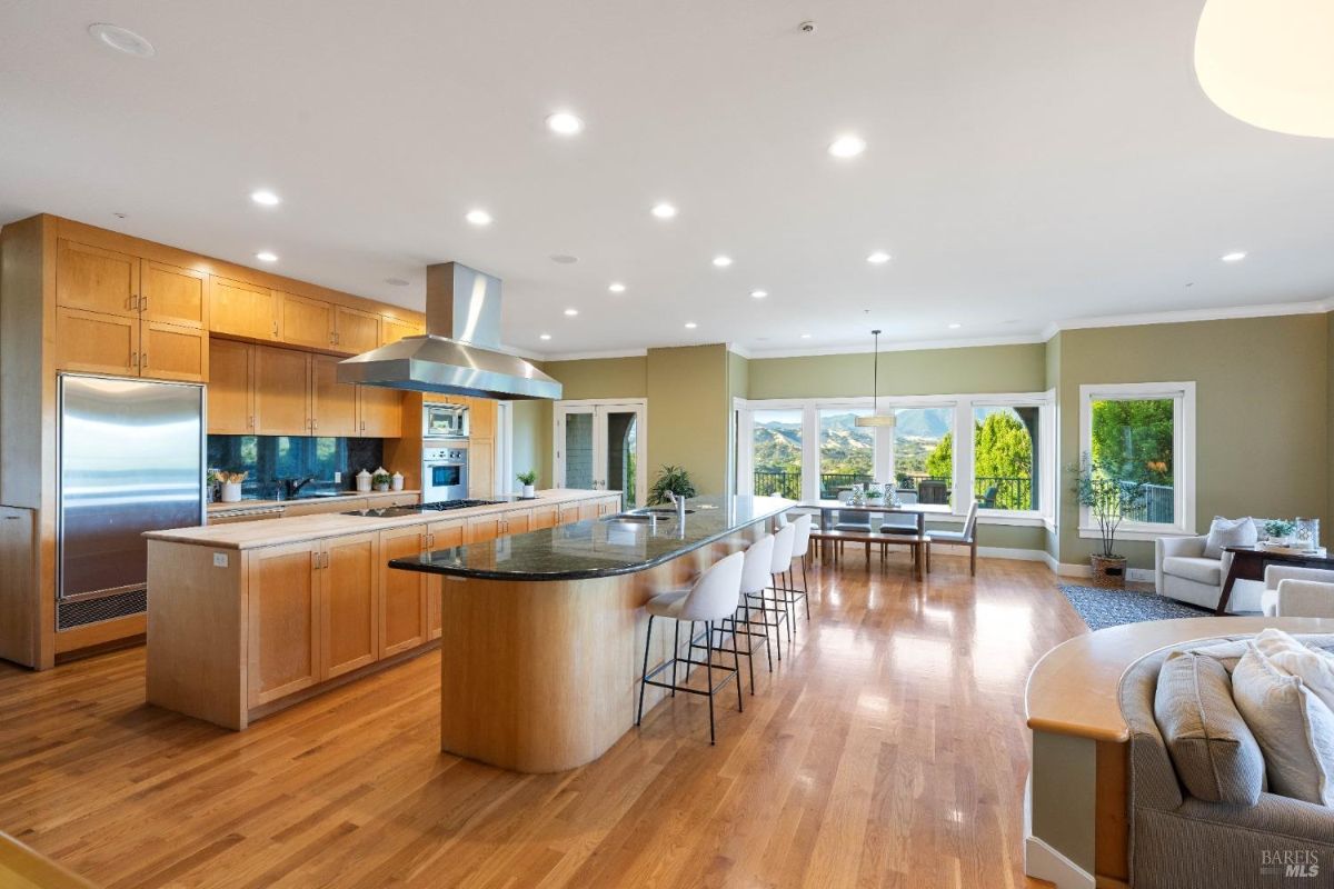 Sleek kitchen with an extended island, modern appliances, and adjacent dining space with expansive windows providing scenic outdoor views.