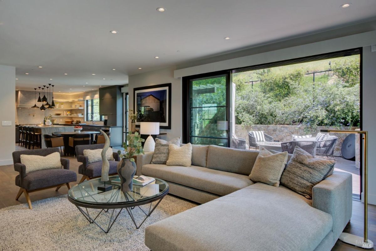 An open-concept living area with a large sectional sofa, a glass coffee table, and access to an outdoor patio.