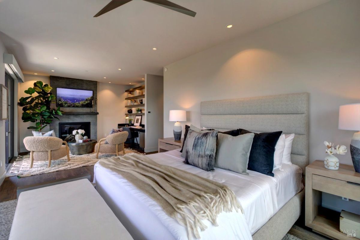 Bedroom with a fireplace, built-in shelving, and a small desk adjacent to a cozy seating area.